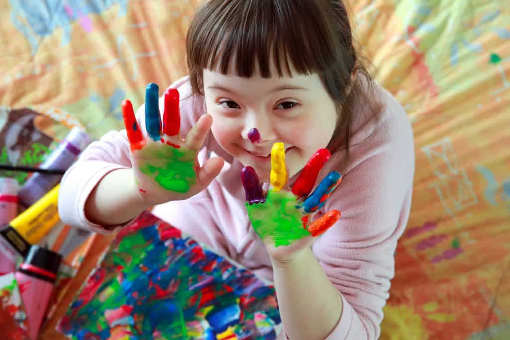 Downsyndrome-girl-smiling-with-painted-hands-1024x683